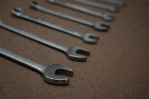 combination wrenches with rings and open ends lined up on a wooden board in workshop selective focus on spanner fixed jaw and background and foreground blur