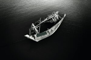 a grayscale of a sinking fishing boat